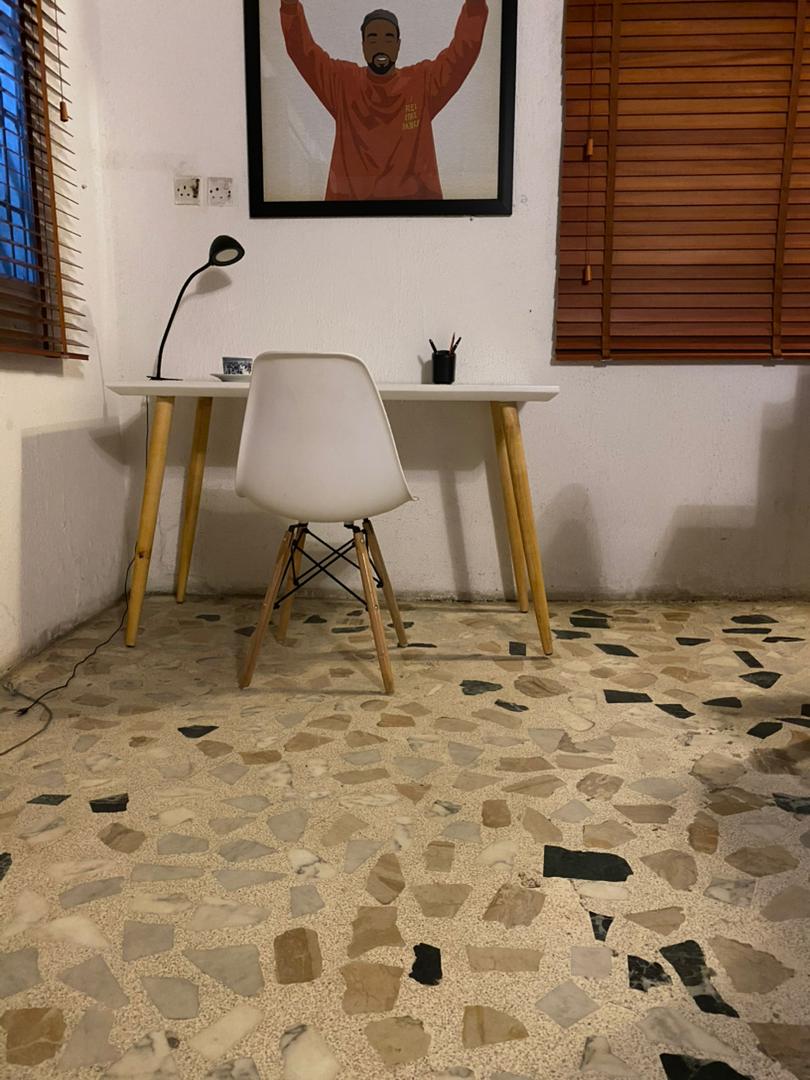 Desk workspace in a room at Ajala Homes with terrazzo floor, timber shutters, and wall art
