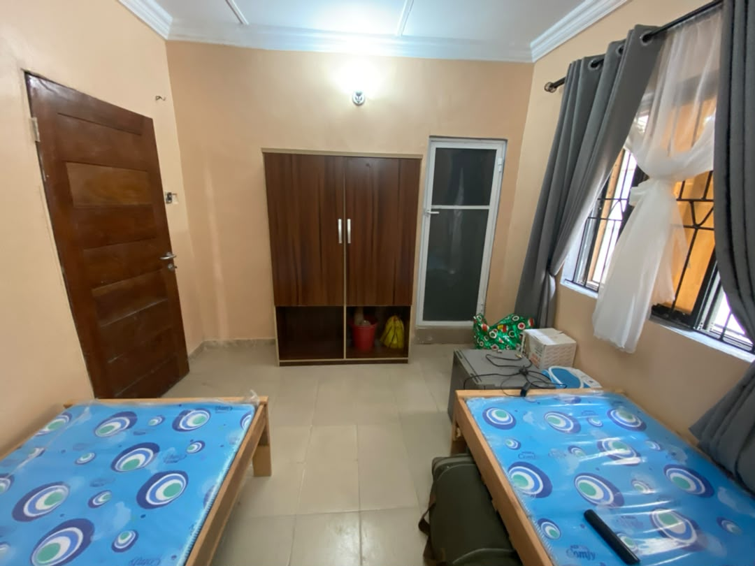 Bed space room at Rilwan AJALA Homes with two beds, wardrobe and curtains