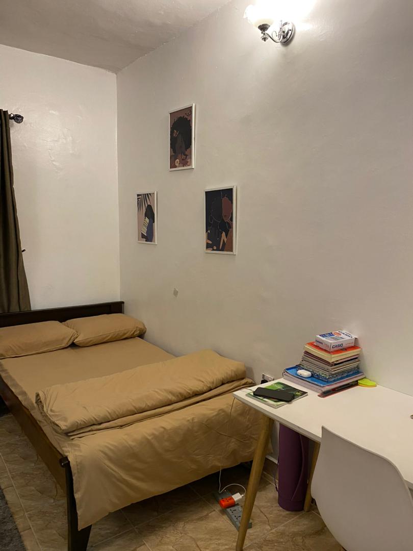 Cosy single room with African wall art prints and bedside desk at Ajala Homes Lagos Mainland