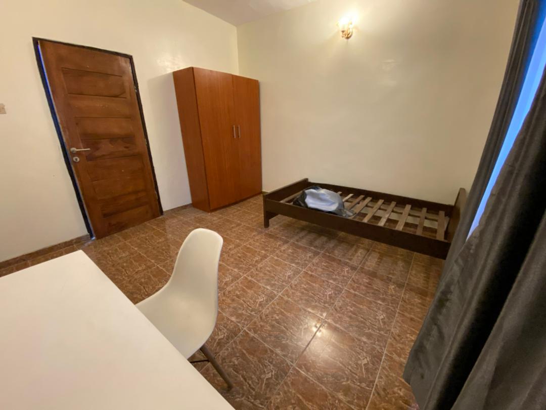 Standard room with wardrobe, single bed frame, and clean tiled floor at Ajala Homes Lagos
