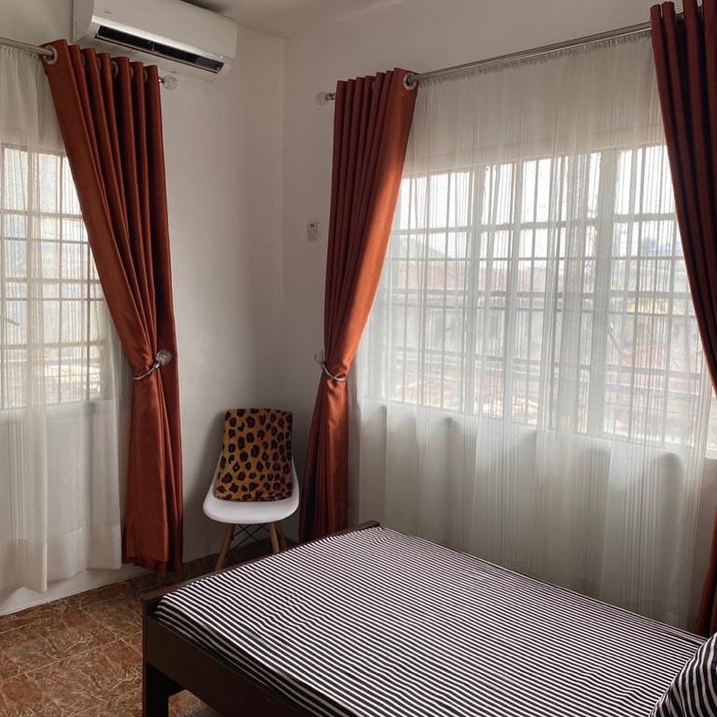 Single room with terracotta curtains and air conditioning at Rilwan AJALA Homes