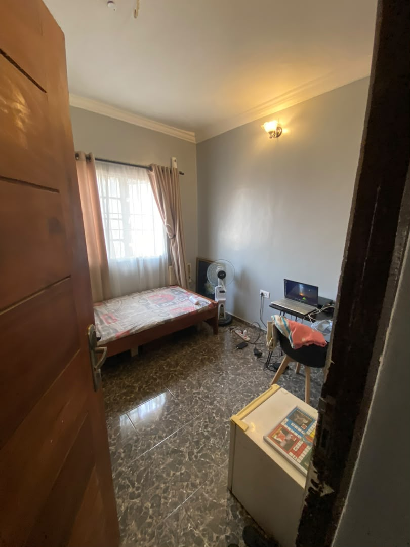 Single room at Rilwan AJALA Homes with grey walls, single bed, desk and fan